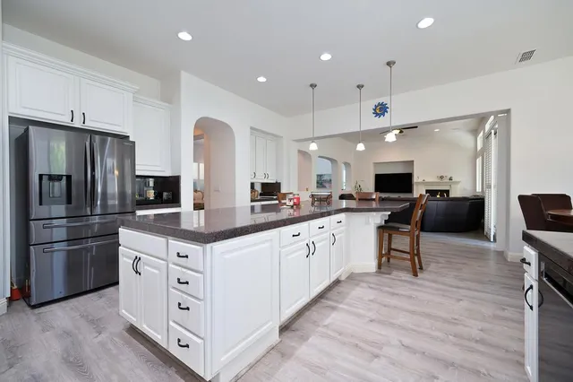 a kitchen with stainless steel appliances kitchen island granite countertop a refrigerator and a stove top oven