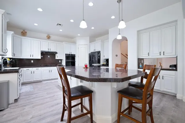 a kitchen with kitchen island a dining table chairs and a refrigerator
