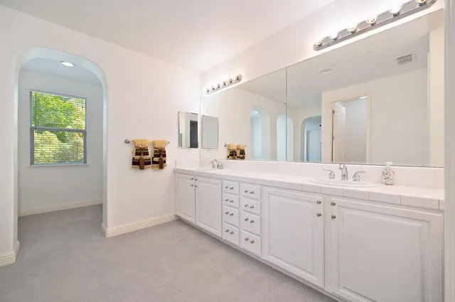 a spacious bathroom with a double vanity sink a mirror and a bathtub