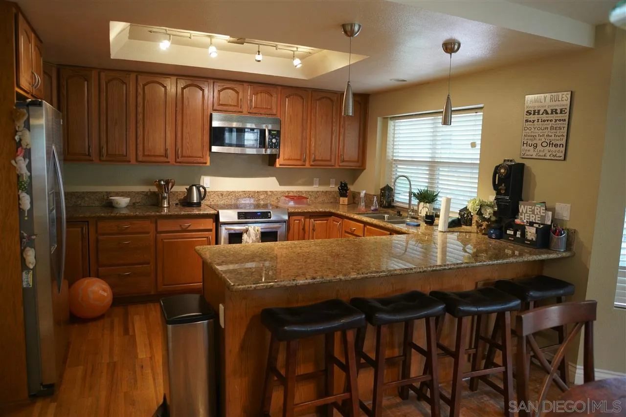 12701 Triumph Drive Poway, CA 92064 - Photo 6 of 21 a kitchen with a table chairs sink and cabinets