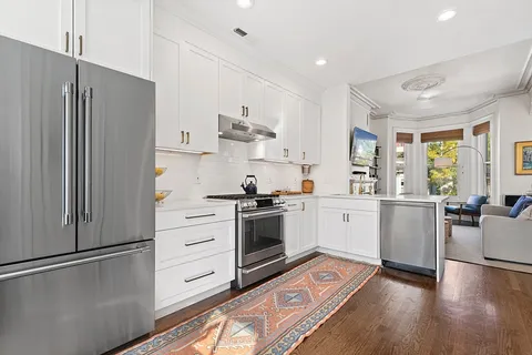 a kitchen with a refrigerator stove and wooden floor