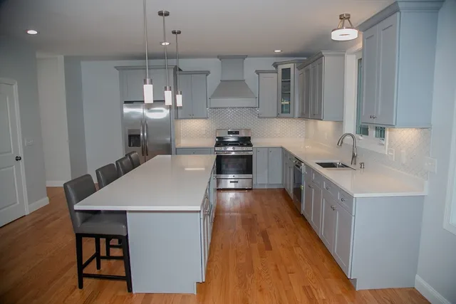 a kitchen with stainless steel appliances a white stove top oven a sink dishwasher and a refrigerator with wooden floor