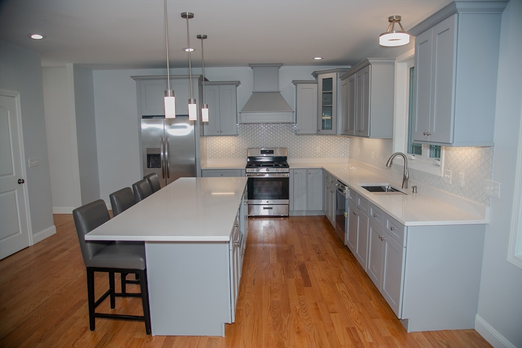 99 West Crystal Brook Drive Springfield, MA 01118 - Photo 14 of 40 a kitchen with stainless steel appliances a white stove top oven a sink dishwasher and a refrigerator with wooden floor
