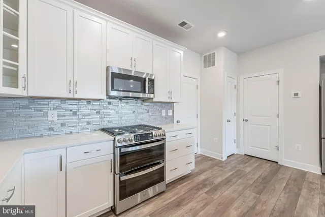 a kitchen with stainless steel appliances white cabinets and a stove top oven