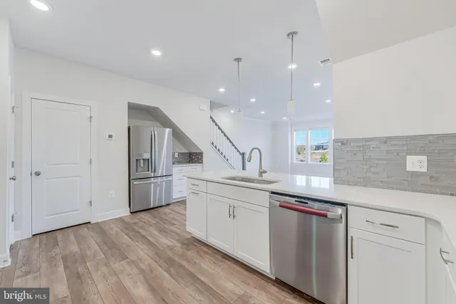 a kitchen with stainless steel appliances granite countertop a sink a stove and a wooden floors