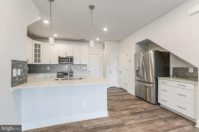 a large kitchen with stainless steel appliances a large counter top a stove a refrigerator and cabinets