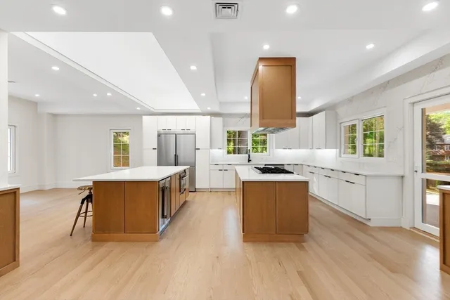 a large kitchen with stainless steel appliances a large counter top a stove a chimney a sink and a large window