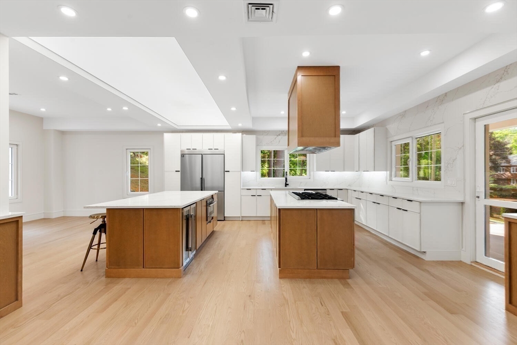 58 Chestnut Street Lynnfield, MA 01940 - Photo 9 of 42 a large kitchen with stainless steel appliances a large counter top a stove a chimney a sink and a large window