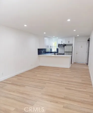 a view of kitchen with kitchen island a sink wooden floor and a refrigerator