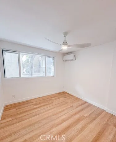 an empty room with wooden floor fan and windows