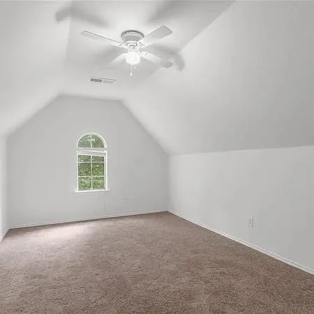 an empty room with a window and ceiling fan