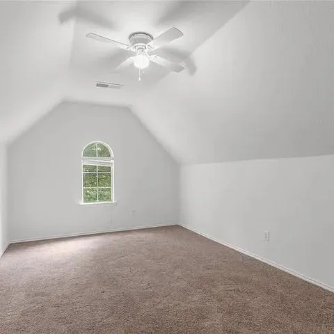 an empty room with a window and ceiling fan