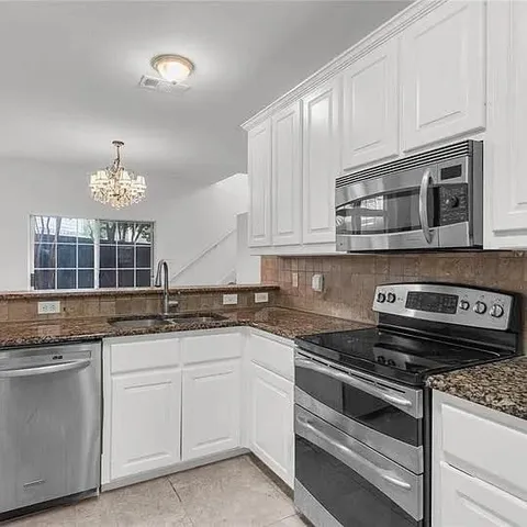 a kitchen with granite countertop white cabinets and stainless steel appliances