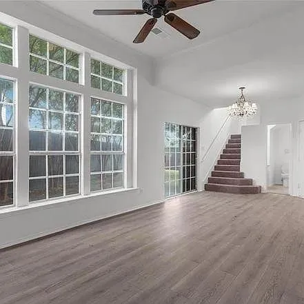 a view of an empty room with wooden floor and windows