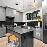 a kitchen with stainless steel appliances granite countertop a stove a refrigerator a sink a dining table and chairs with wooden floor