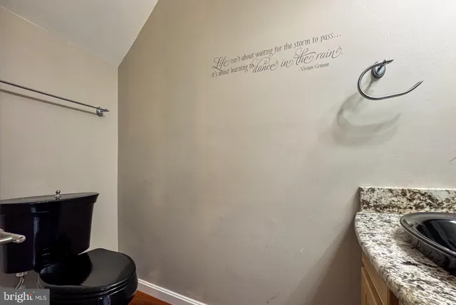 a bathroom with a granite countertop a sink a toilet and a mirror