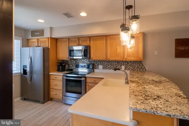 a kitchen with stainless steel appliances granite countertop a refrigerator a stove a sink and a center island