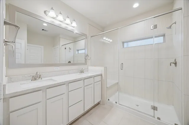 a bathroom with a double vanity sink mirror and shower