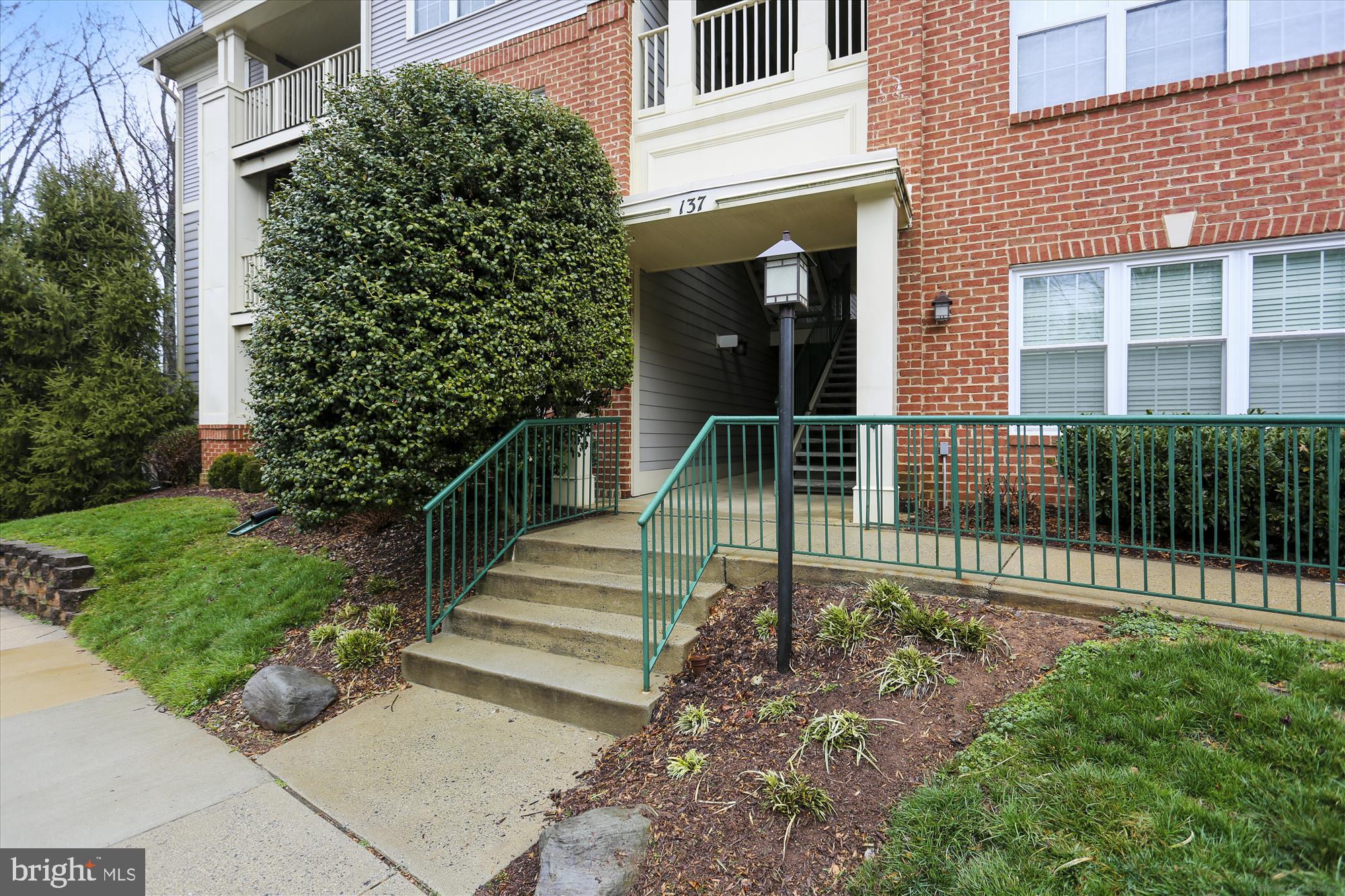 137 Timberbrook Lane, Unit 103 Gaithersburg, MD 20878 - Photo 2 of 51 a view of a house with a small yard and flower plants