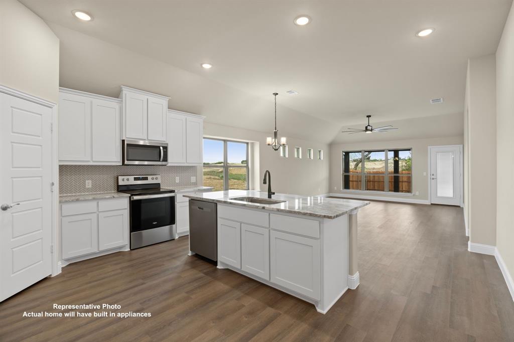 448 Mcalpine Springtown, TX 76082 - Photo 3 of 9 a kitchen with stainless steel appliances kitchen island granite countertop a stove and a sink