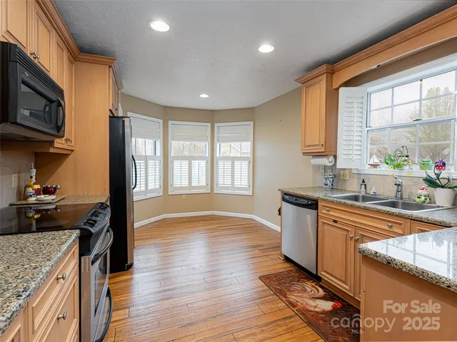 a large kitchen with stainless steel appliances granite countertop a stove a sink and a microwave