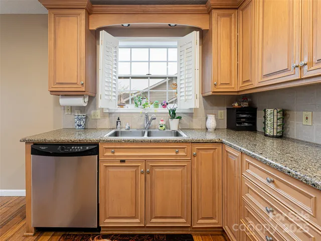 a kitchen with granite countertop a sink stainless steel appliances and cabinets