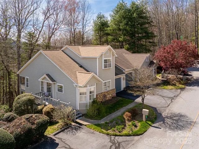 a view of a house with a yard and large trees