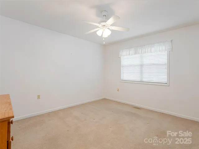 an empty room with windows and chandelier fan