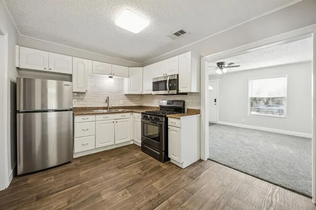 a kitchen with cabinets stainless steel appliances and sink