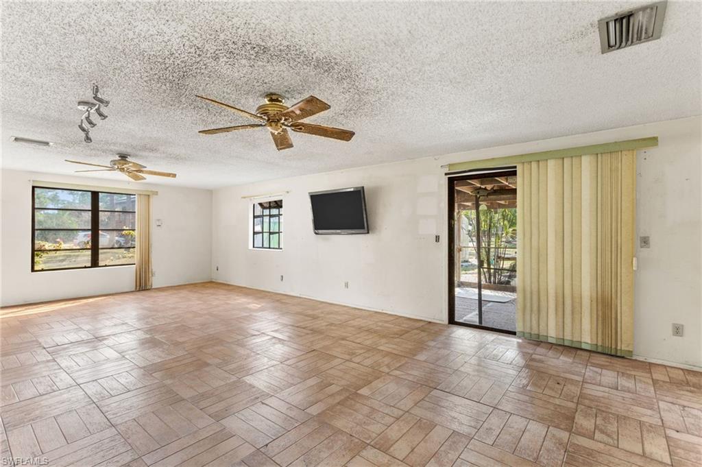 465 5th Street Southwest Naples, FL 34117 - Photo 12 of 33 Empty room with plenty of natural light, a ceiling fan, and a textured ceiling