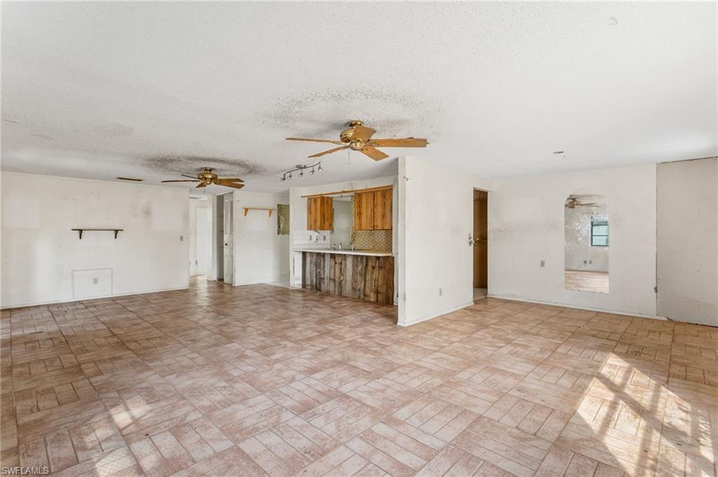 465 5th Street Southwest Naples, FL 34117 - Photo 13 of 33 Unfurnished living room featuring a textured ceiling and a ceiling fan