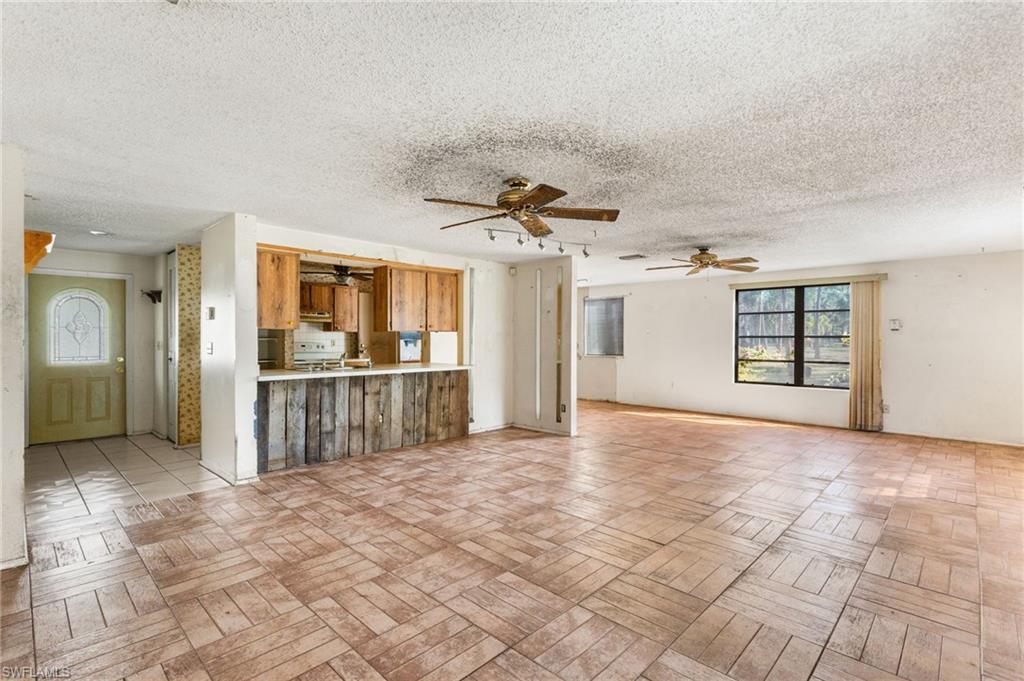 465 5th Street Southwest Naples, FL 34117 - Photo 14 of 33 Unfurnished living room featuring a textured ceiling and ceiling fan