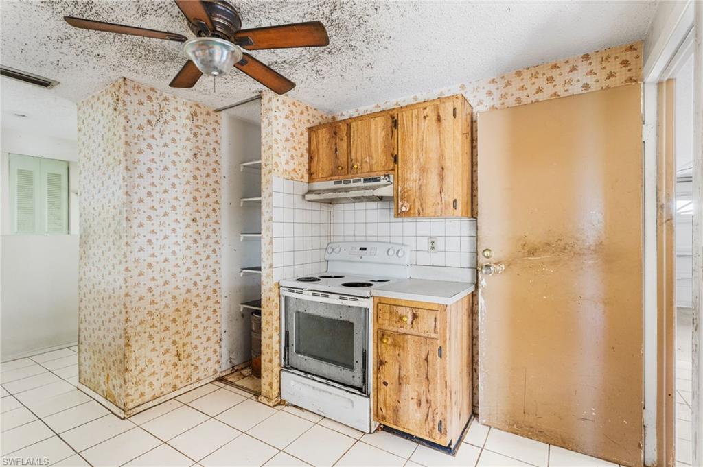 465 5th Street Southwest Naples, FL 34117 - Photo 16 of 33 Kitchen with white electric range oven, a textured ceiling, light countertops, a ceiling fan, and light tile patterned flooring