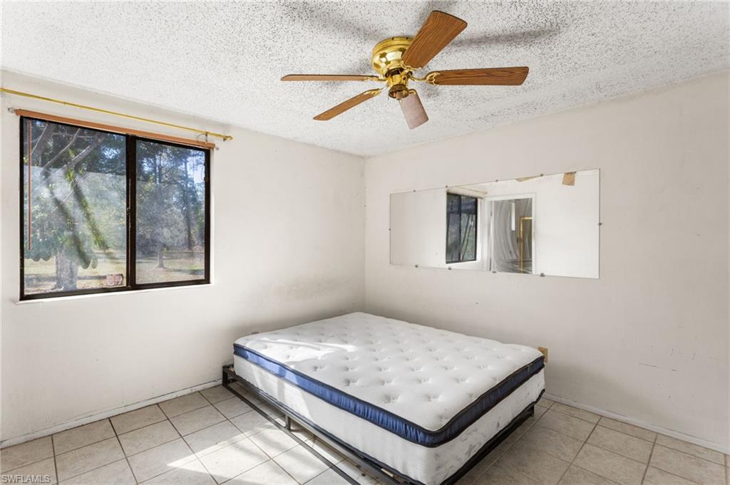 465 5th Street Southwest Naples, FL 34117 - Photo 18 of 33 Bedroom featuring a textured ceiling, a ceiling fan, and light tile patterned flooring