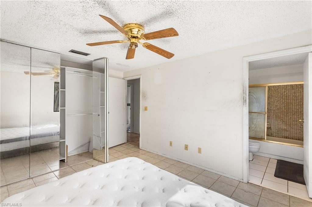 465 5th Street Southwest Naples, FL 34117 - Photo 19 of 33 Unfurnished bedroom featuring a textured ceiling, a ceiling fan, ensuite bathroom, and light tile patterned floors
