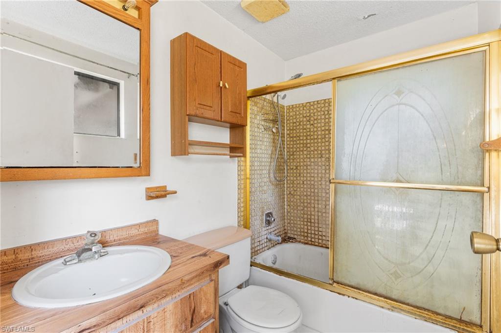 465 5th Street Southwest Naples, FL 34117 - Photo 20 of 33 Full bathroom with enclosed tub / shower combo, vanity, and a textured ceiling