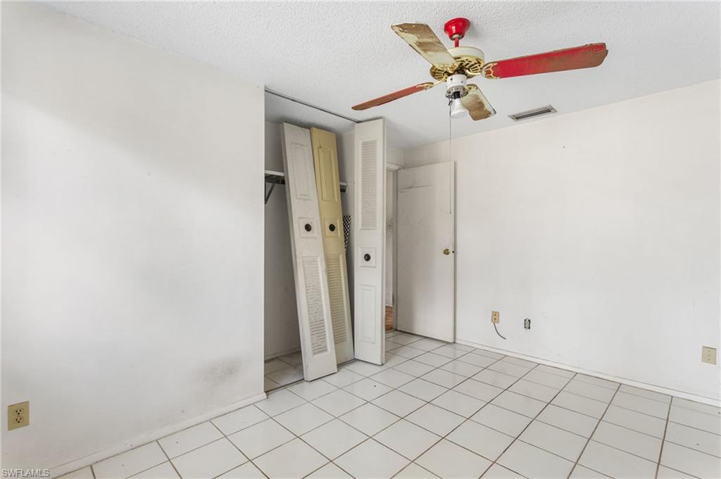 465 5th Street Southwest Naples, FL 34117 - Photo 22 of 33 Unfurnished bedroom featuring a ceiling fan, a textured ceiling, a closet, and light tile patterned floors