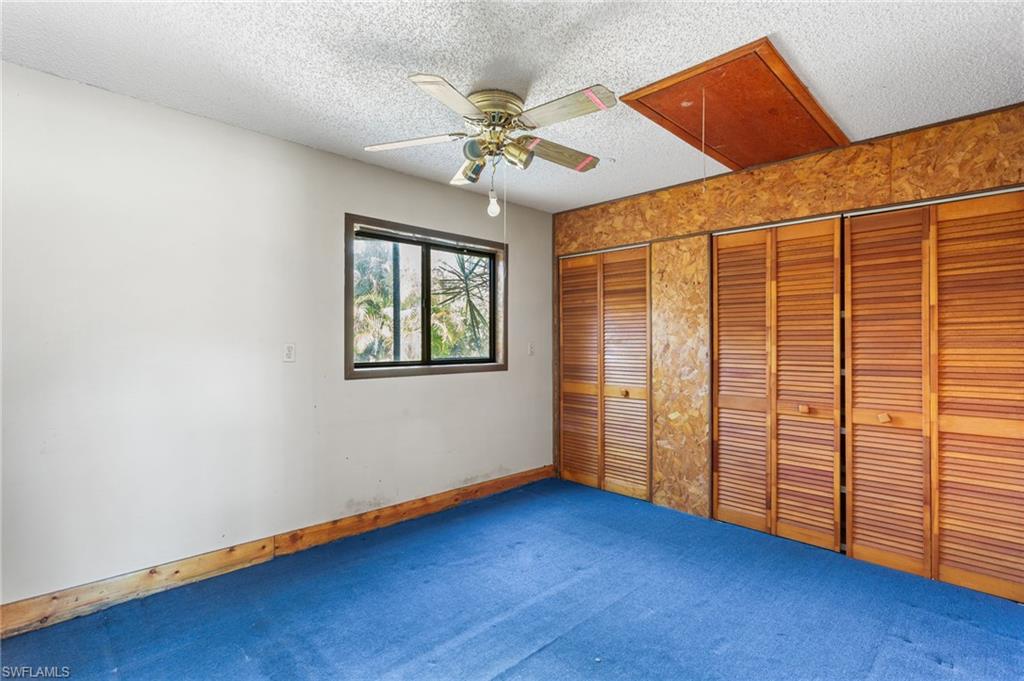 465 5th Street Southwest Naples, FL 34117 - Photo 27 of 33 Unfurnished bedroom featuring two closets, a textured ceiling, a ceiling fan, and carpet floors