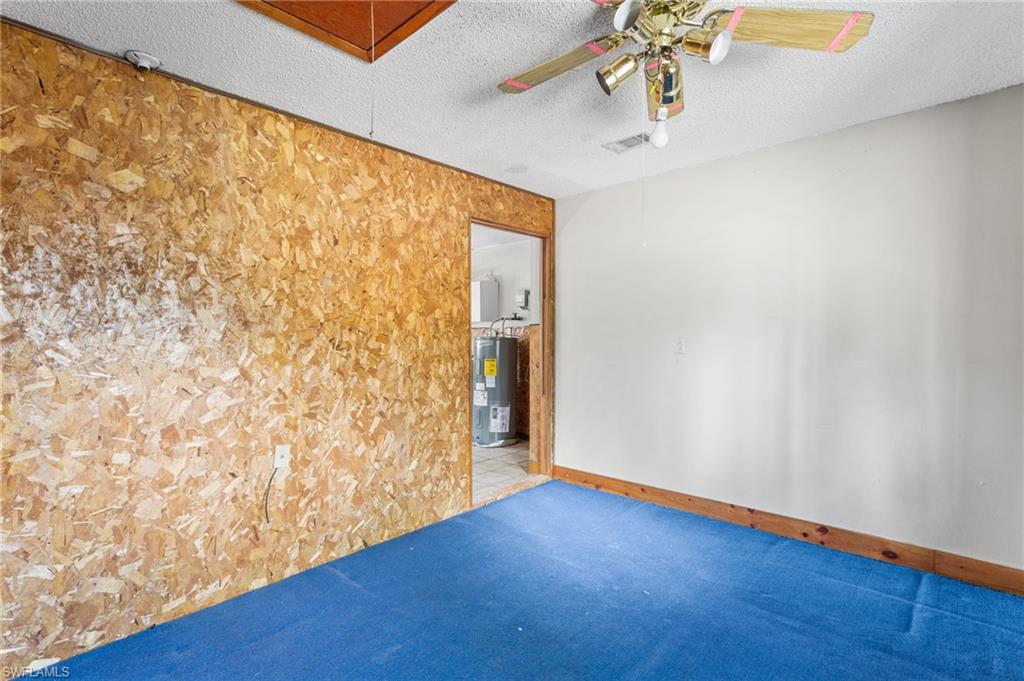 465 5th Street Southwest Naples, FL 34117 - Photo 28 of 33 Spare room with a textured ceiling, a ceiling fan, electric water heater, and carpet flooring
