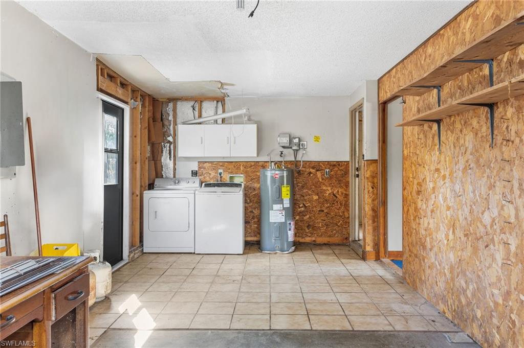 465 5th Street Southwest Naples, FL 34117 - Photo 29 of 33 Laundry room with a textured ceiling, washer and clothes dryer, cabinet space, water heater, and wainscoting