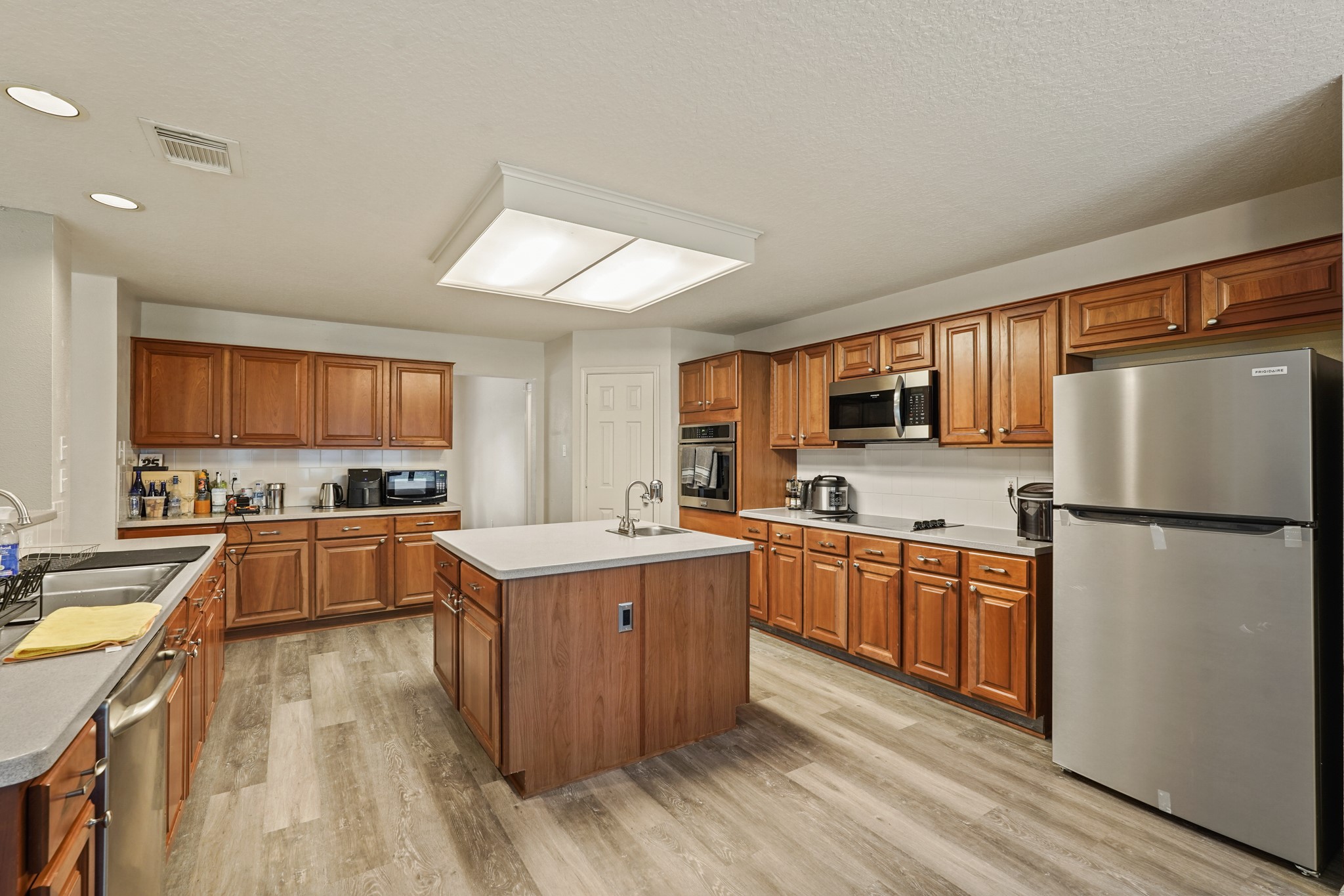 14616 Grant Road Cypress, TX 77429 - Photo 7 of 18 a kitchen with stainless steel appliances granite countertop a refrigerator a stove top oven a sink dishwasher and white cabinets with wooden floor