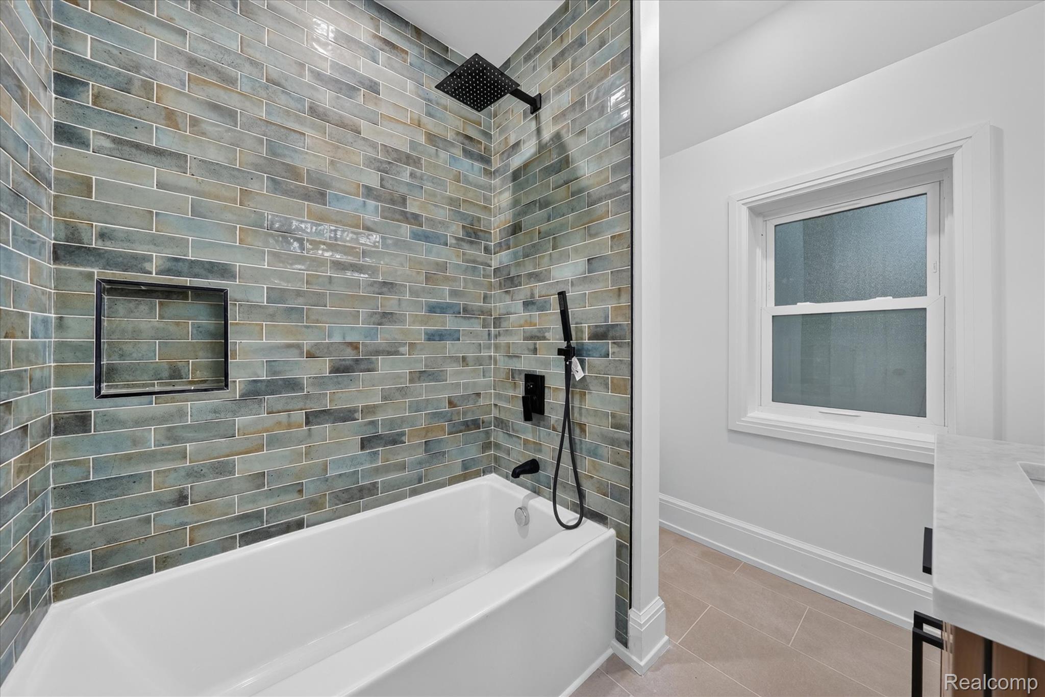 3250 Sherbourne Road Detroit, MI 48221 - Photo 19 of 36 Bathtub featuring tiled surround with recessed niche, matte black shower fixtures, and a single window with white trim