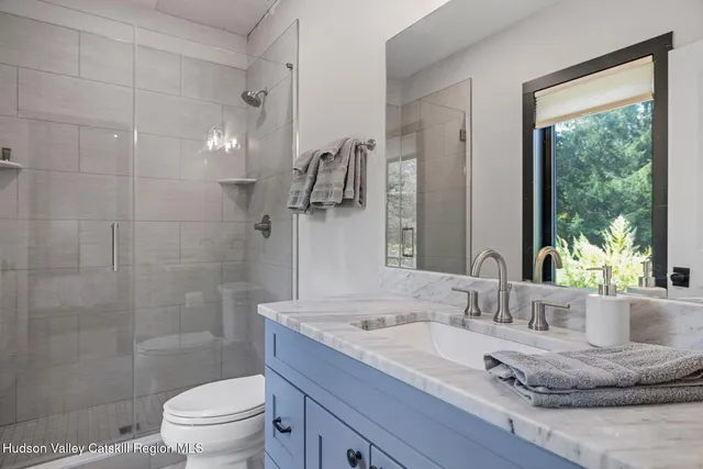 a bathroom with a granite countertop sink a toilet and a mirror