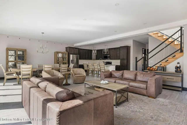 a living room with furniture kitchen view and a wooden floor