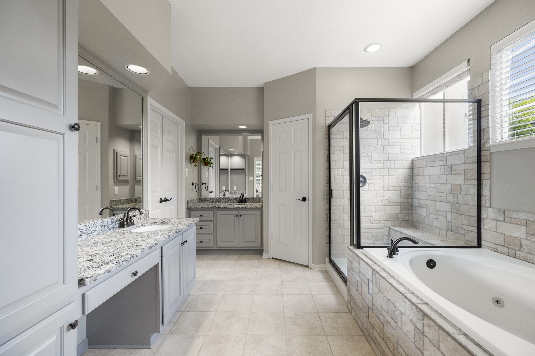102 Treescape Circle Spring, TX 77381 - Photo 13 of 40 This spacious primary bathroom features a modern design with a large glass-enclosed shower, a soaking tub, granite countertops, dual sinks, and ample cabinet storage. Natural light floods in through the windows, enhancing the airy feel.
