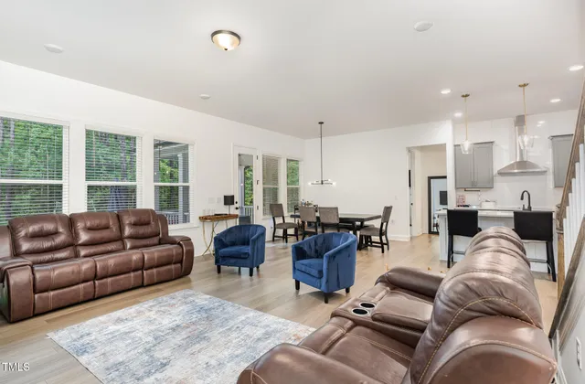 a living room with furniture kitchen view and a large window