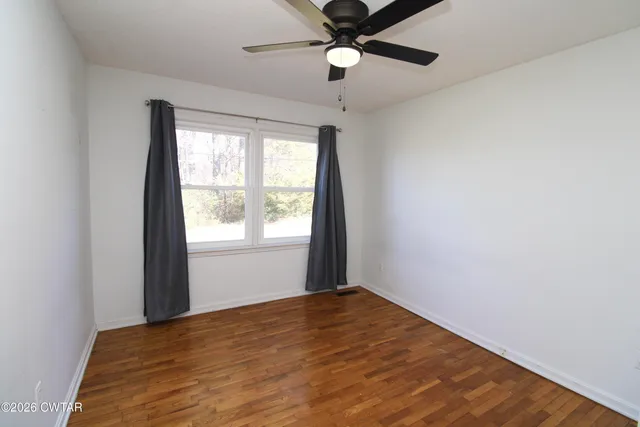 an empty room with a window and a ceiling fan