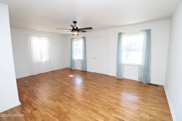 a view of empty room with window and ceiling fan