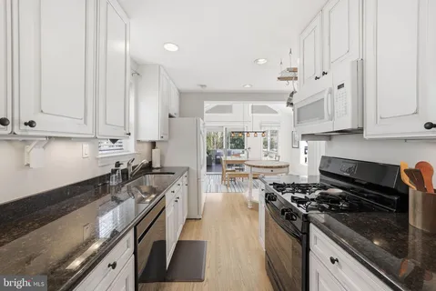 a kitchen with stainless steel appliances granite countertop a stove and a white cabinets