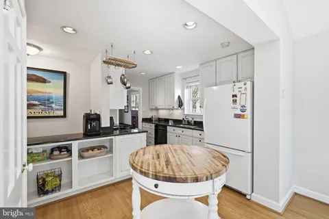 a kitchen with stainless steel appliances a stove a refrigerator a sink a dining table and chairs with wooden floor